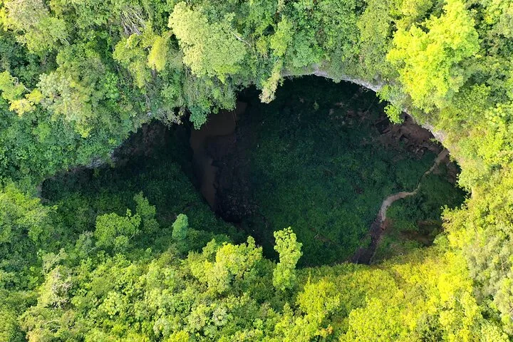 Aerial view looking down into a massive green sinkhole